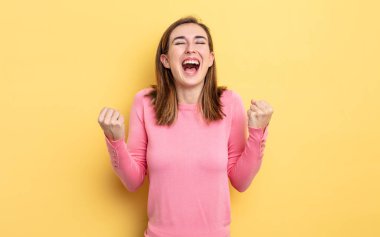 Genç ve güzel kız son derece mutlu ve şaşırmış görünüyor, başarıyı kutluyor, bağırıyor ve zıplıyor.