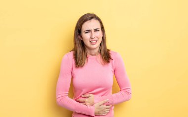 Genç, güzel bir kız endişeli, hasta, hasta ve mutsuz hissediyor. Ağrılı bir mide ağrısı ya da grip geçiriyor.