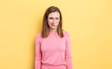 Genç ve güzel kız mutlu ve arkadaş canlısı görünüyor, gülümsüyor ve pozitif bir tavırla sana göz kırpıyor.