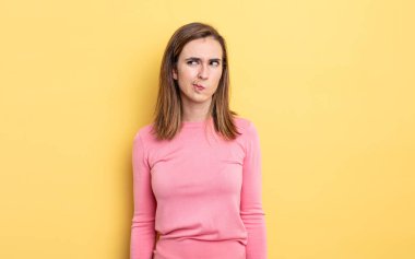 Genç ve güzel kız kafası karışmış görünüyor, merak ediyor veya bir sorunu çözmeye çalışıyor veya düşünüyor.