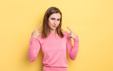 Kötü tavırlı genç ve güzel bir kız gururlu ve agresif görünüyor, yukarıyı işaret ediyor ya da elleriyle alay işareti yapıyor.