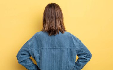 Genç, güzel bir kız, kafası karışık ya da dolu ya da şüphe ve soru dolu, merak ediyor, elleri kalçasında, dikiz aynasından.