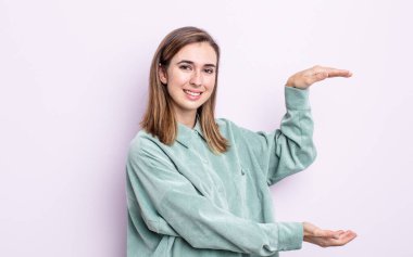 Genç güzel kız gülümsüyor, mutlu, pozitif ve tatmin olmuş hissediyor, fotokopi alanında nesne ya da konsept tutuyor ya da gösteriyor