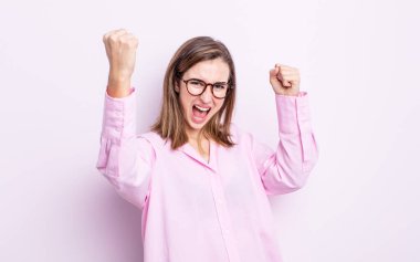 Genç ve güzel bir kız muzaffer bir şekilde bağırıyor. Heyecanlı, mutlu ve şaşırmış görünüyor. Kutlama yapıyor.