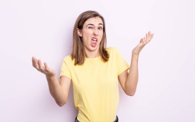 young pretty girl shrugging with a dumb, crazy, confused, puzzled expression, feeling annoyed and clueless