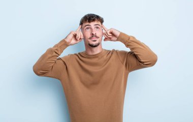 Genç ve yakışıklı bir adam kafası karışmış ya da şüphe içinde, bir fikre odaklanmış, çok düşünüyor, kenarda boşluğu kopyalamaya çalışıyor.