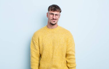 Genç yakışıklı adam mutlu ve arkadaş canlısı görünüyor, gülümsüyor ve sana olumlu bir tavırla göz kırpıyor.