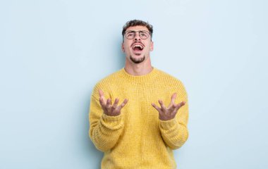 Genç yakışıklı adam umutsuz ve sinirli görünüyor, stresli, mutsuz ve sinirli, bağırıyor ve çığlık atıyor.