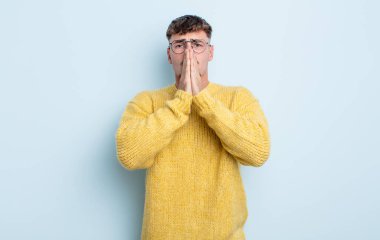 Genç yakışıklı adam endişeli, üzgün ve korkmuş, elleri ağızda, endişeli ve berbat görünüyor.
