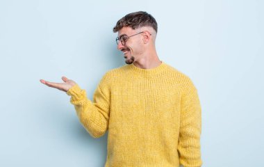 Genç yakışıklı adam kendini mutlu hissediyor ve gülümsüyor. Yanında duran bir nesneye ya da konsepte bakıyor.