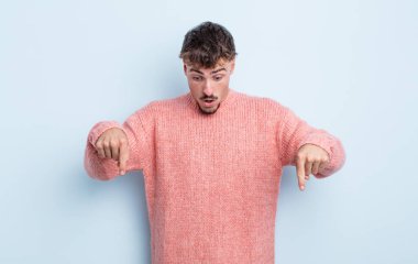 Genç yakışıklı adam şok olmuş, ağzı açık ve şaşkın, inançsızlık ve şaşkınlık içinde bakıyor ve onu işaret ediyor.