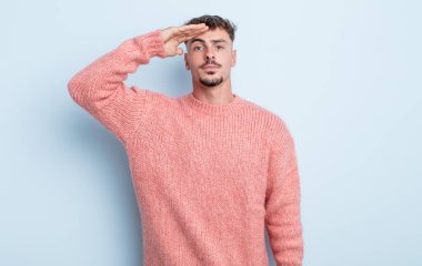 Genç ve yakışıklı bir adam saygı göstererek, onur ve vatanseverlik adına askeri bir selamla kamerayı selamlıyor.