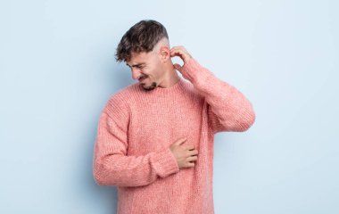 Genç ve yakışıklı bir adam stresli, hayal kırıklığına uğramış ve yorgun, endişeli ve sorunlu bir bakışla boynunu okşuyor.