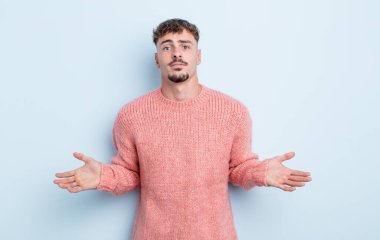 Genç yakışıklı adam şaşkın ve şaşkın hissediyor, doğru cevap veya karardan emin değil, bir seçim yapmaya çalışıyor.