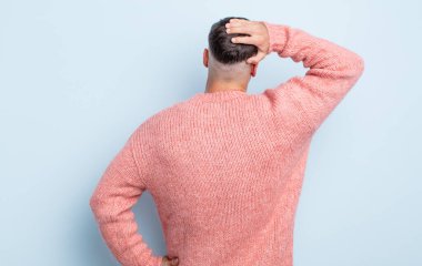 Genç yakışıklı bir adam bilgisiz ve kafası karışık hissediyor, bir çözüm düşünüyor, eli kalçasında, diğeri kafasında, dikiz aynasından.