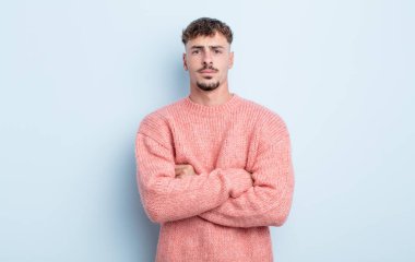 Genç yakışıklı adam hayal kırıklığına uğramış ve hayal kırıklığına uğramış, ciddi görünüyor, kızgın ve kollarını kavuşturmuş.