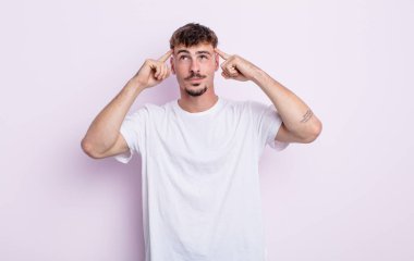 Genç ve yakışıklı bir adam kafası karışmış ya da şüphe içinde, bir fikre odaklanmış, çok düşünüyor, kenarda boşluğu kopyalamaya çalışıyor.