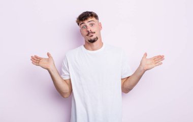 Genç yakışıklı adam şaşkın ve şaşkın, şüpheci, farklı seçenekleri tartıyor ya da komik bir ifadeyle seçiyor.