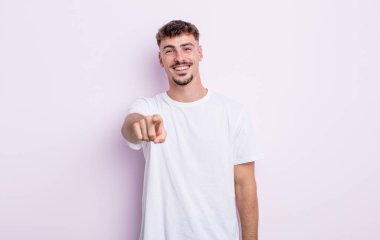 Genç ve yakışıklı bir adam kameraya bakıyor. Tatmin olmuş, kendine güvenen, dost canlısı bir gülümsemeyle seni seçiyor.