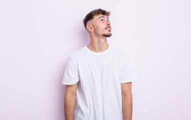 Endişeli, kafası karışık, budala bir ifadeyle genç yakışıklı adam, kopya alanı arıyor, şüphe ediyor.