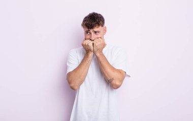 Genç yakışıklı adam endişeli, endişeli, stresli ve korkmuş görünüyor, tırnaklarını yiyor ve yanal fotokopi alanı arıyor.