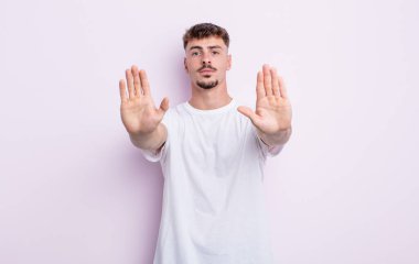 Genç yakışıklı adam ciddi, mutsuz, kızgın ve hoşnutsuz görünüyor. Ya da her iki avuçta da dur diyor.