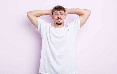 Genç ve yakışıklı bir adam stresli, endişeli, endişeli ya da korkmuş, elleri başının üstünde, hata yaptığında panikliyor.