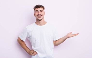 Genç yakışıklı adam gülümsüyor, kendinden emin, başarılı ve mutlu hissediyor, fotokopi alanında fikir veya konsept gösteriyor.