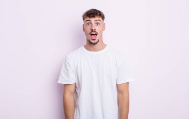 Genç ve yakışıklı bir adam şok olmuş ya da şaşırmış görünüyor, ağzı açık bir şekilde 
