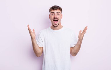Genç yakışıklı adam mutlu, heyecanlı, şaşırmış ya da şok olmuş hissediyor, gülümsüyor ve hayrete düşüyor.