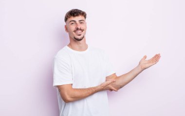 Genç yakışıklı adam gururla ve kendinden emin bir şekilde gülümsüyor, mutlu ve tatmin olmuş hissediyor ve fotokopi alanında bir konsept gösteriyor.