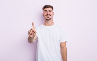 Genç yakışıklı adam gülümsüyor ve arkadaş canlısı görünüyor, bir numara ya da ilk eli önde, geriye doğru sayıyor.