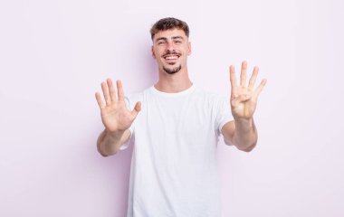 Genç yakışıklı adam gülümsüyor ve arkadaş canlısı görünüyor. 9 ya da 9 numarayı gösteriyor. Elleri önde, geriye doğru sayıyor.