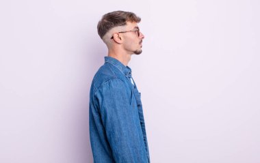 Profil görünümündeki genç yakışıklı adam ilerideki boşluğu kopyalamaya çalışıyor, düşünüyor, hayal ediyor ya da hayal kuruyor.