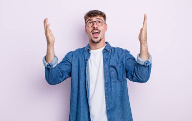 Genç yakışıklı adam kendini mutlu, şaşkın, şanslı ve şaşırmış hissediyor. Zaferi kutlarken iki elini de havaya kaldırıyor.