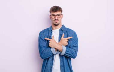 Şaşkın, kafası karışmış, güvensiz ve şüpheyle zıt yönlere bakan genç yakışıklı bir adam.