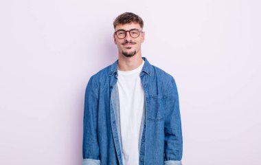 Genç yakışıklı adam pozitif ve kendinden emin gülümsüyor. Tatmin olmuş, arkadaş canlısı ve mutlu görünüyor.