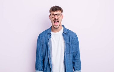 Genç yakışıklı adam agresif bir şekilde bağırıyor, çok kızgın, hayal kırıklığına uğramış, öfkeli ya da sinirli görünüyor, hayır