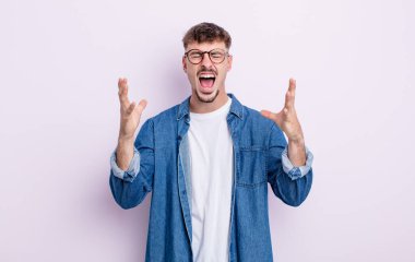 Genç yakışıklı adam öfkeyle bağırıyor, stresli hissediyor ve ellerini havaya kaldırıp neden ben diye bağırıyor.
