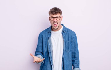 Genç yakışıklı adam sinirli, sinirli ve sinirli görünüyor. Senin neyin var?