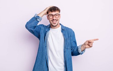 Genç yakışıklı adam gülüyor, mutlu, pozitif ve şaşırmış görünüyor. Yan fotokopi alanını işaret eden harika bir fikrin farkına varıyor.