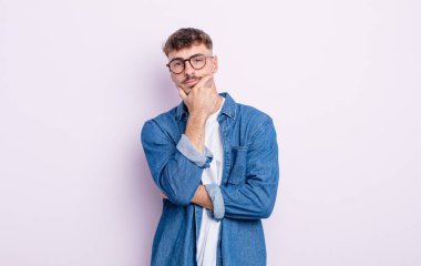 Genç yakışıklı adam ciddi görünüyor, kafası karışık, kararsız ve düşünceli, seçenekler ve seçimler arasında şüpheci.