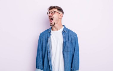 Genç yakışıklı adam öfkeyle bağırıyor, agresif bir şekilde bağırıyor, stresli ve sinirli görünüyor.