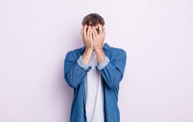 Genç ve yakışıklı bir adam korkmuş ya da utanmış hissediyor. Gözleri yarı kapalı ya da ellerle dikizliyor ya da dikizliyor.