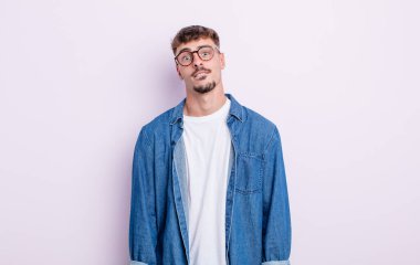 Şaşkın ve kafası karışmış genç bir adam gergin bir hareketle dudağını ısırıyor, sorunun cevabını bilmiyor.