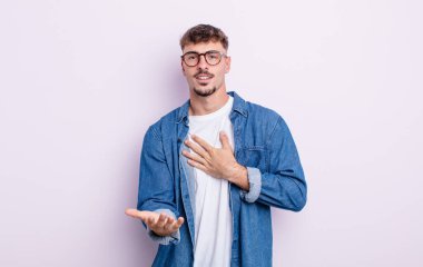 Genç yakışıklı adam mutlu ve aşık, bir eli kalbinin yanında, diğer eli önde uzanmış gülümsüyor.