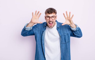 Genç ve yakışıklı bir adam panik ya da öfke içinde bağırıyor, şok olmuş, korkmuş ya da öfkeli, elleri başının yanında.