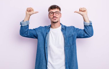Genç yakışıklı adam gururlu, kibirli ve kendinden emin, tatmin olmuş ve başarılı görünüyor, kendini işaret ediyor.