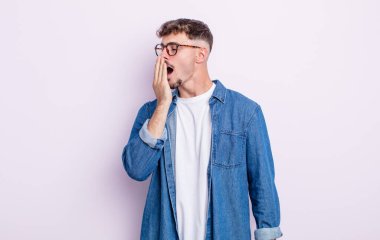 Genç yakışıklı adam tembelce esniyor, uykulu, yorgun ve sıkkın görünüyor.