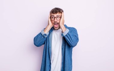 Genç yakışıklı adam mutlu, heyecanlı ve şaşırmış hissediyor, iki eli yüzü yana bakıyor.